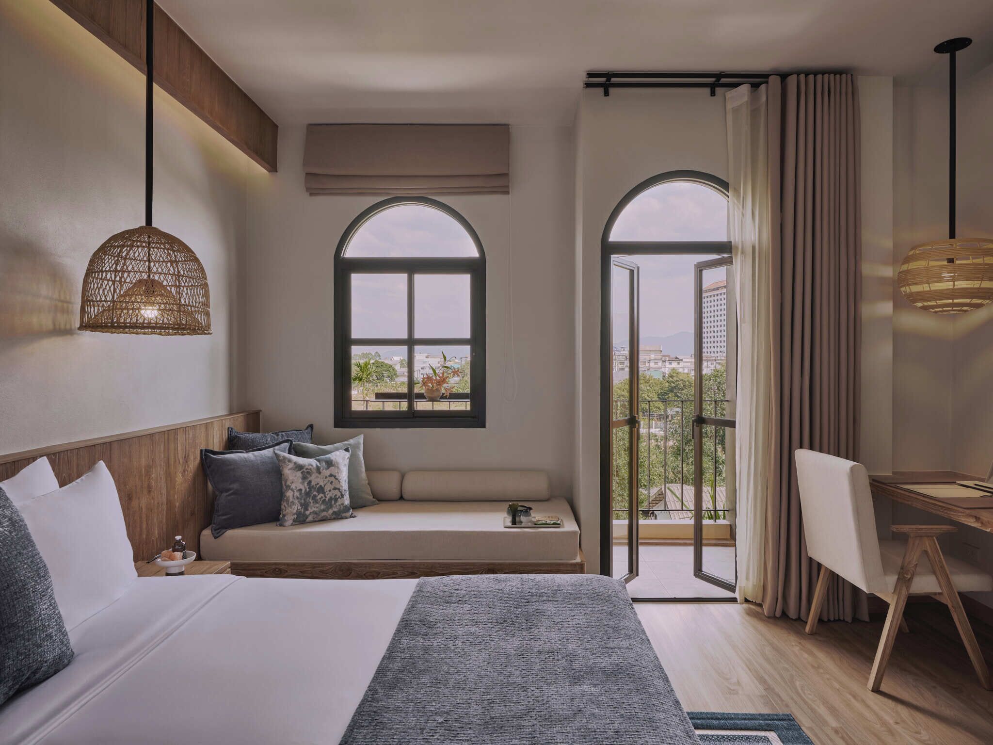 Habitación de hotel con cama, zona de estar con vistas, escritorio y ventana grande.