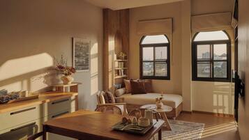 A cozy living room with a dining area, a sofa, and a window with a view of buildings.