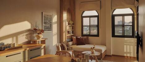 Una sala de estar acogedora con comedor, un sofá y una ventana con vistas a edificios.