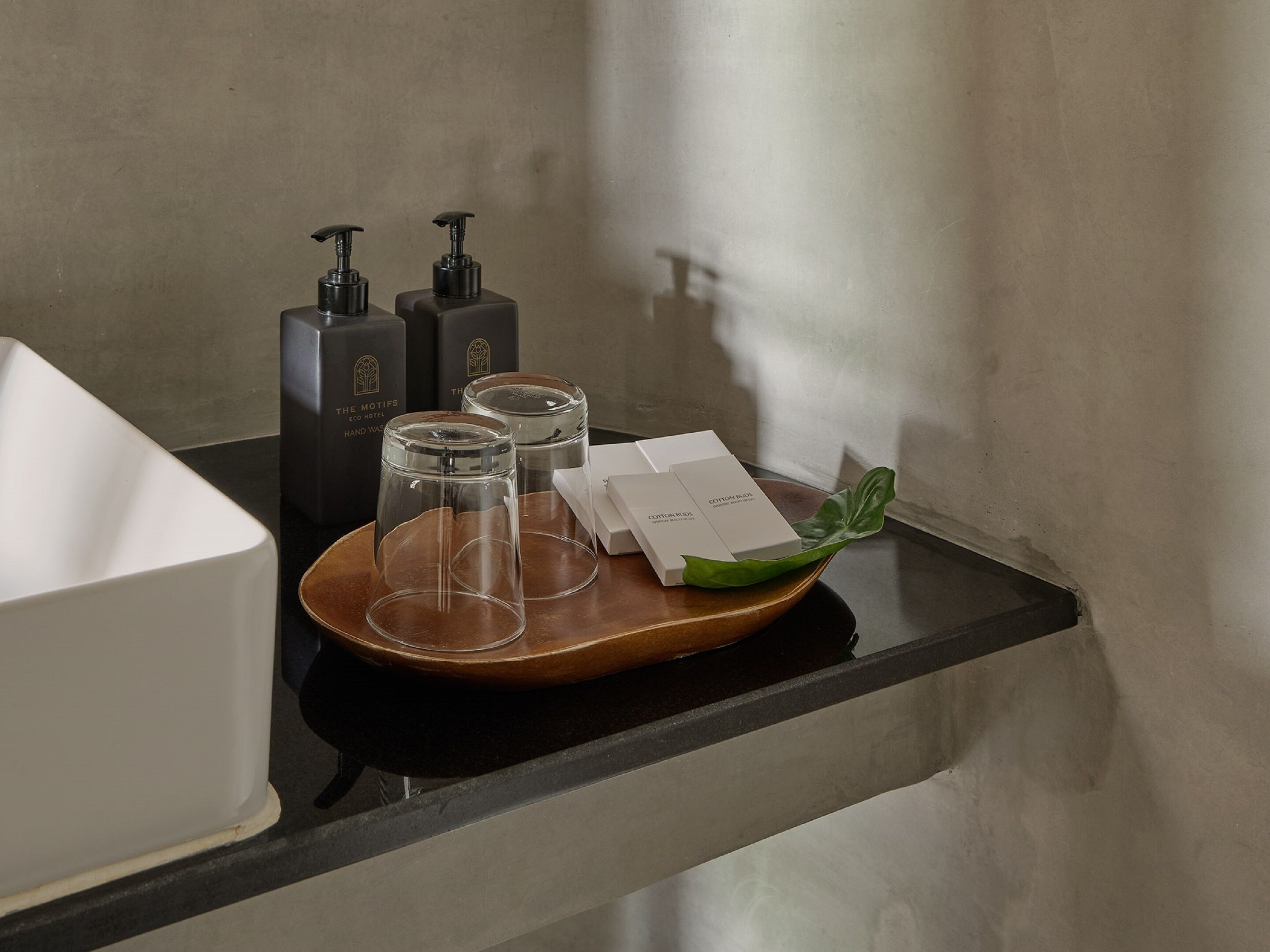 A tray with glassware, a white box, and two black bottles on a black countertop.