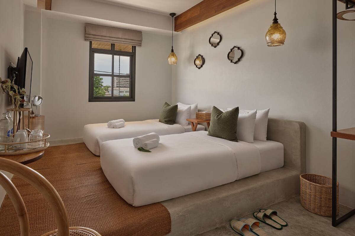 Une chambre d’hôtel avec deux lits, un plafond en bois, une fenêtre donnant sur un beau paysage et un miroir au mur.
