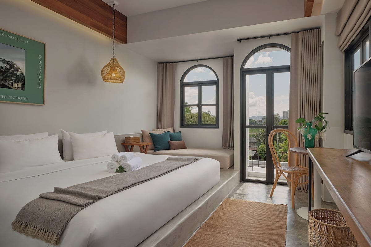 Une chambre d’hôtel moderne, dotée d’un grand lit, d’un bureau et offrant une vue sur l’extérieur.