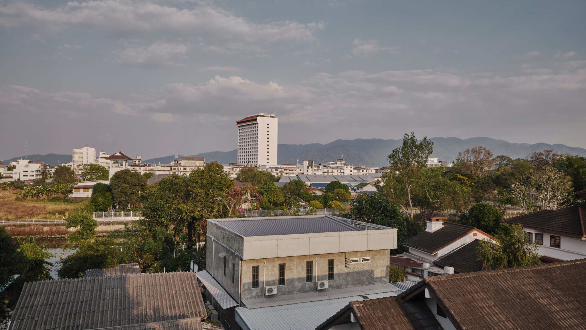 A residential area with a mix of modern and traditional buildings, including a prominent high-rise building in the background.