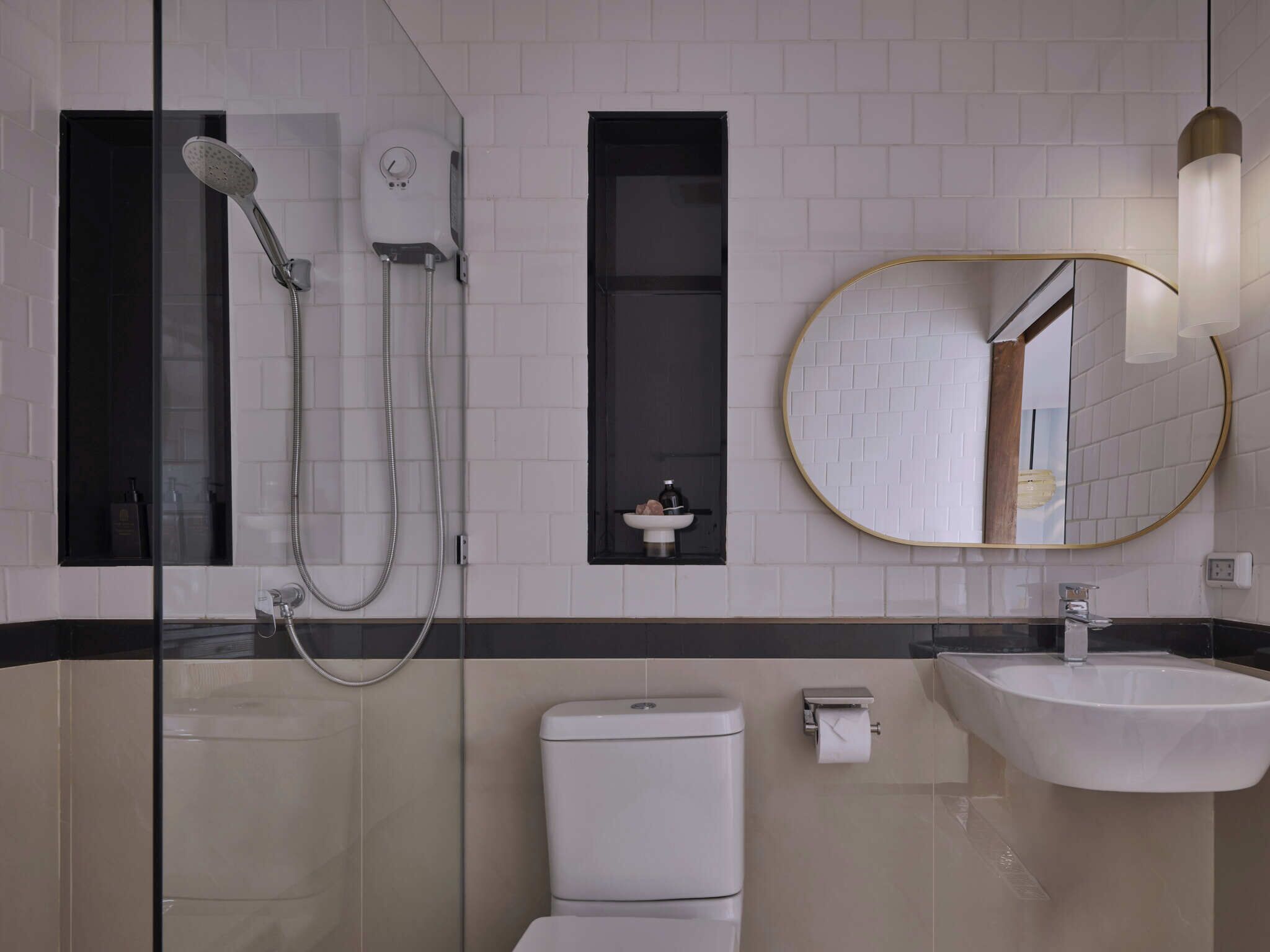 A modern bathroom with a glass-enclosed shower, a toilet, a sink, and a mirror with a gold frame.