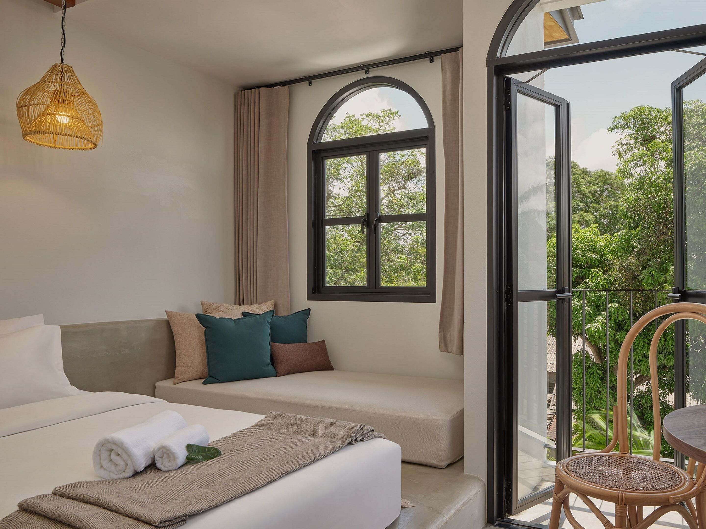 A modern room with a sofa, a dining table, and a large window with a view of greenery.