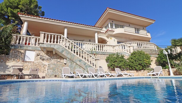 Ein großes Haus mit Schwimmbad, Treppe und Balkon.
