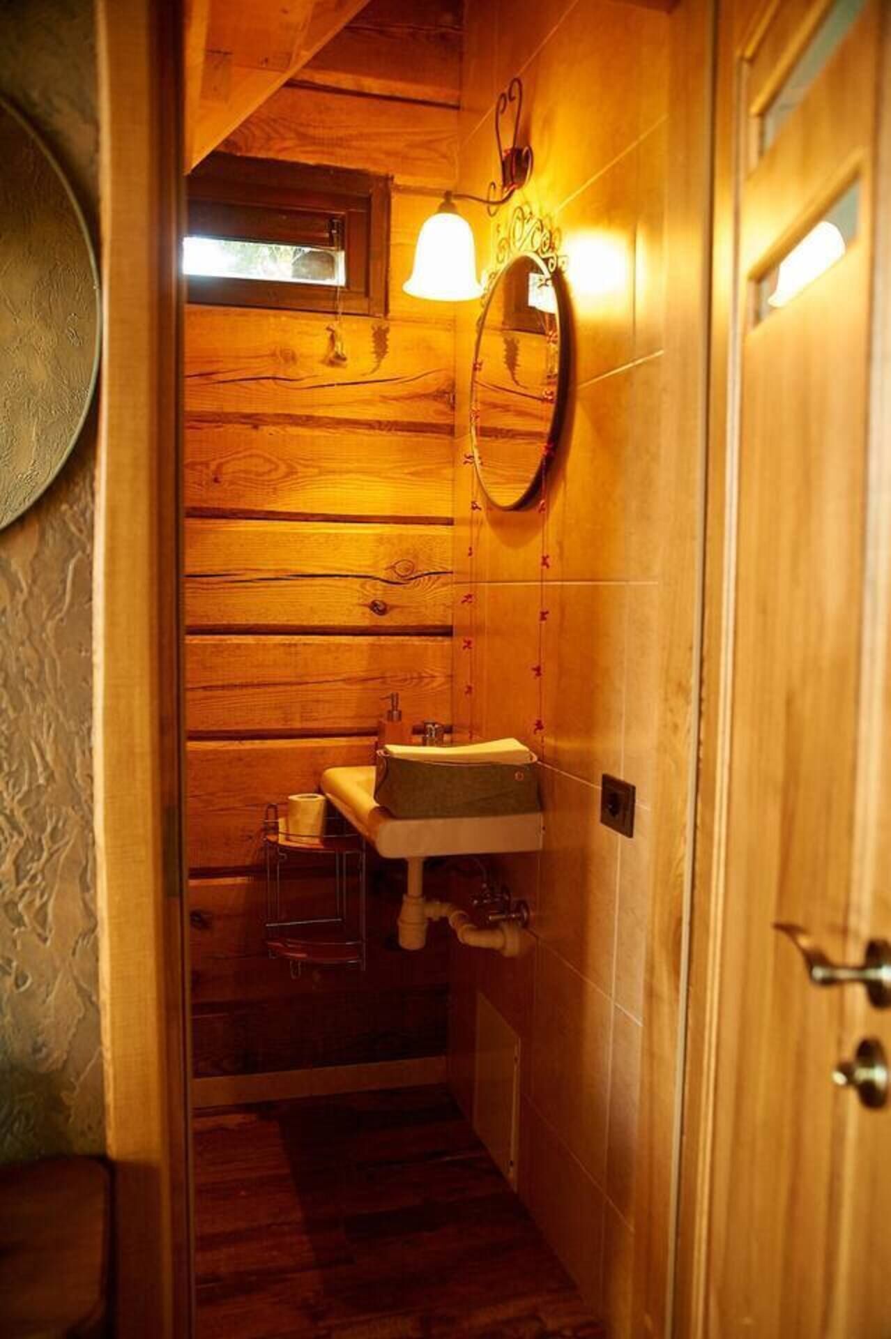 A wooden bathroom with a sink, mirror, and a small window.
