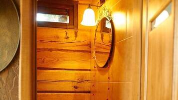A wooden bathroom with a sink, mirror, and a small window.