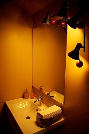 A bathroom with a sink, mirror, and two wall-mounted lamps. - Villa With Sauna and hot tub on the Lakeshore (Kuliai)