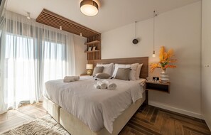 Une chambre à coucher moderne avec un grand lit, une tête de lit en bois, des tables de chevet et un vase de fleurs.