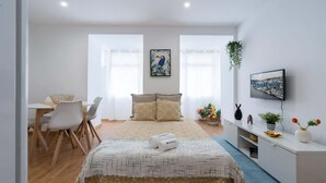 Ein Schlafzimmer mit Bett, Nachttisch, Fernseher und Schreibtisch mit Stühlen.