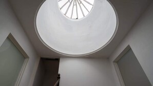 Ein Oberlicht in einem Zimmer mit weißen Wänden und einer Holztreppe.