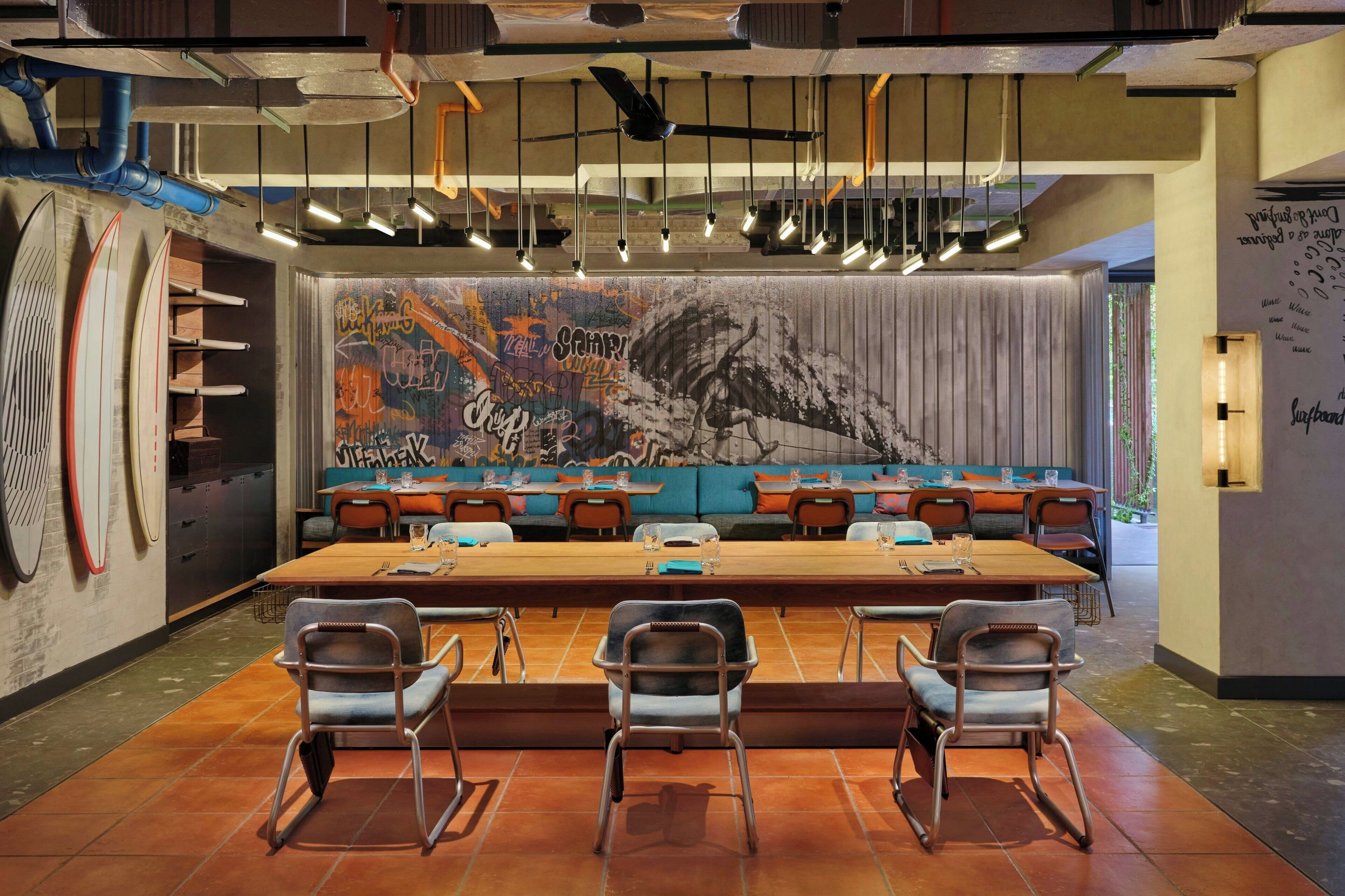 A conference room with a long table, chairs, and a mural on the back wall.