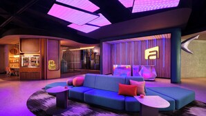 A modern lounge area with a blue sofa, small tables, and a bar with a 'Fuel' sign. - Aloft by Marriott Bali Kuta at Beachwalk (Kuta)