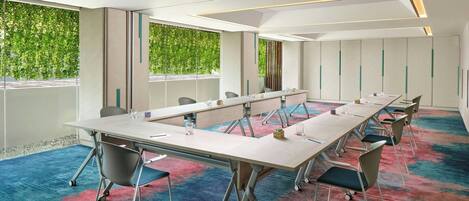 A conference room with a long table, chairs, and a carpeted floor.