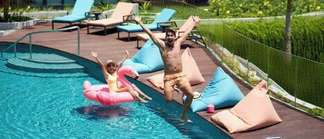 Zona de piscina con sillones de descanso y terraza de madera.