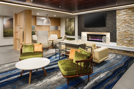 A modern living room with a fireplace, comfortable seating, and a large flat-screen TV mounted on the wall.