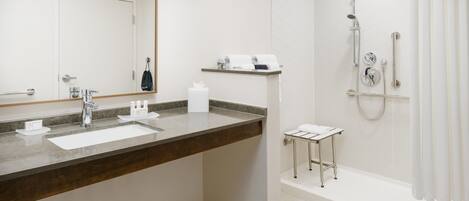 Un baño moderno con un lavabo grande, una ducha y un espejo.