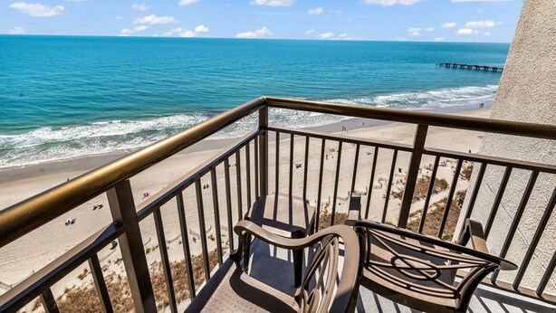 A balcony with a view of the ocean, a sandy beach, and a pier in the distance. - Wow-Fabulous Oceanfront 15th floor 2 Balconies! (Myrtle Beach)