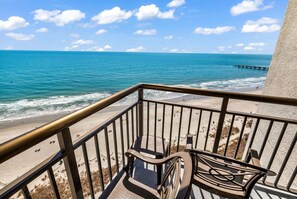 Un balcone con vista sull'oceano, una spiaggia sabbiosa e un molo in lontananza.