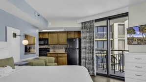 A modern hotel room with a large bed, a kitchenette, a balcony with a view, and a dining area. - Wow-Fabulous Oceanfront 15th floor 2 Balconies! (Myrtle Beach)