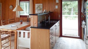 Un interior de madera con una zona de cocina, una mesa de comedor y un ventanal.