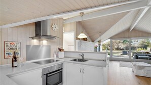 Een moderne keuken met witte kasten, roestvrijstalen apparatuur en een groot raam met uitzicht op een tuin.