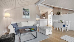 Een moderne, open woonruimte met een bank, salontafel en een eethoek.