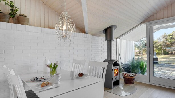 Een moderne keuken met witte bakstenen muren, een witte tafel en een houtkachel.