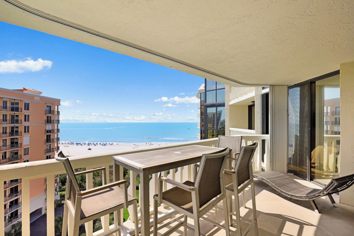 Un balcon avec une table et des chaises donnant sur une plage.