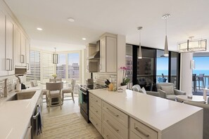 A modern kitchen with a large island, dining area, and a view of the ocean. - Rare Beachfront Condo | Pool, Spa & Tennis (Marco Island)