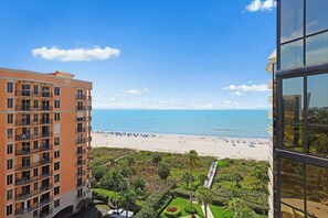 A high-rise hotel with a view of a beach and a landscaped garden.