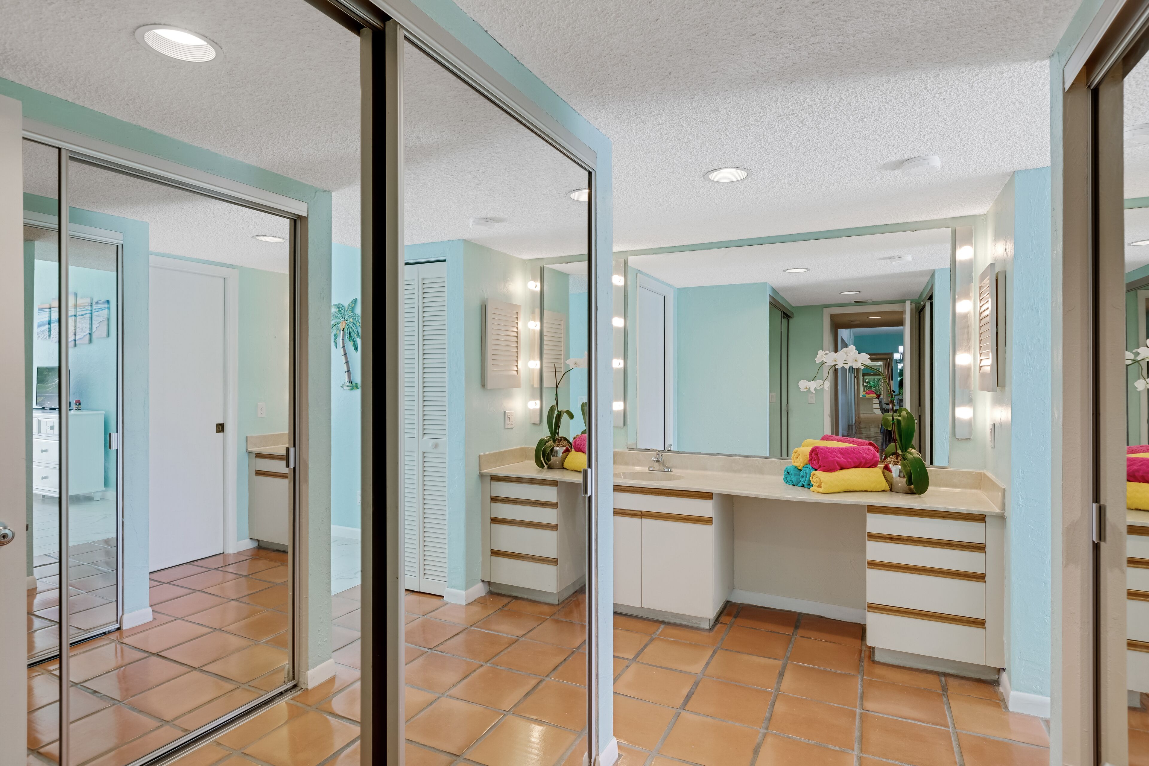 A bathroom with a large mirror, a sink, and a vanity with drawers.