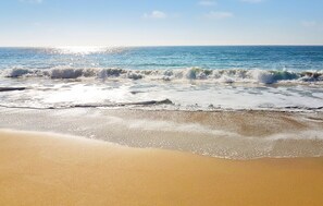 Una playa con olas rompiendo en la orilla y un cielo despejado.