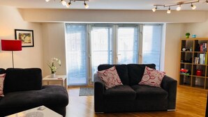 Ein modernes Wohnzimmer mit einer schwarzen Couch, einem weißen Couchtisch und einem Bücherregal.