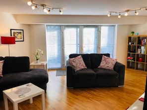Relax in this stylish living room with a sofa, coffee table, and floor lamp, surrounded by books and a personal touch.