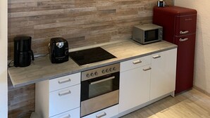 Pieni, käytännöllinen keittiö, jossa on puukuvioitu välitila, sisäänrakennettu uuni, mikroaaltouuni ja punainen, vanhanaikainen jääkaappi.