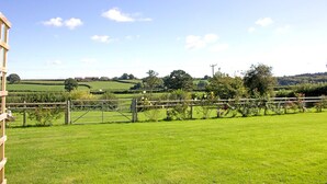 Un paysage rural avec un champ d’herbe, une clôture en bois et un bâtiment en arrière-plan.