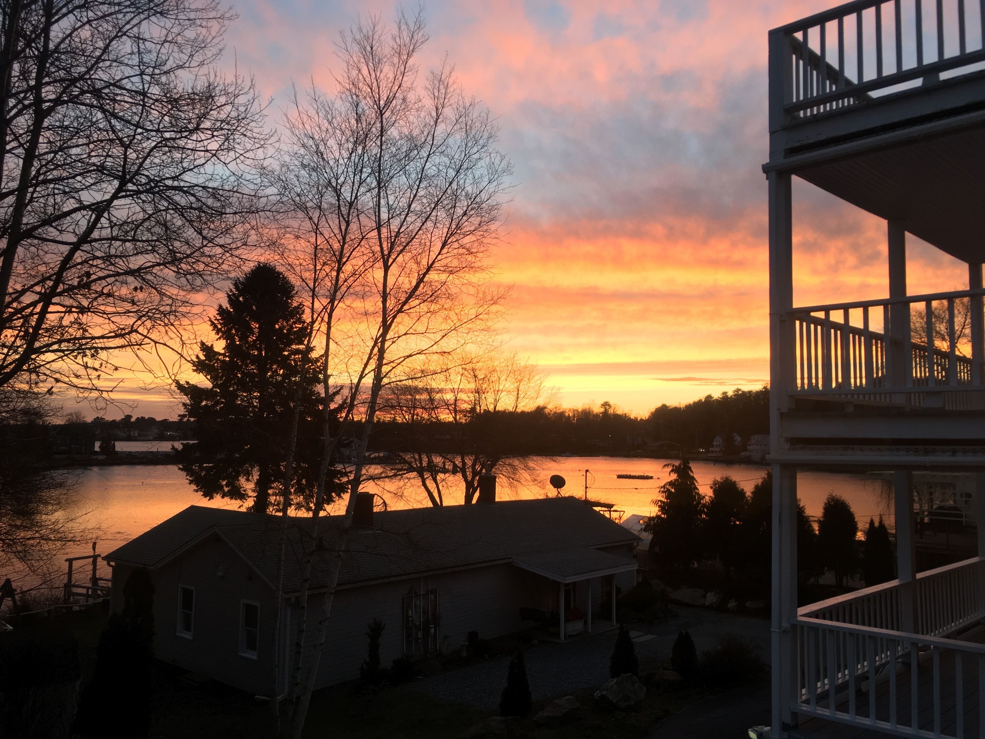 A house with a balcony overlooking a body of water during sunset.