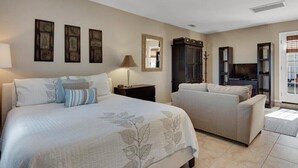 Une chambre d’hôtel comprenant un lit, deux fauteuils, une télévision et une armoire.