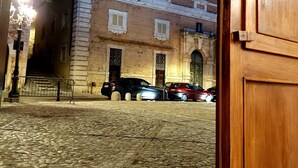 Una entrada a un edifici amb un pati de pedra, una porta de fusta i un fanal.