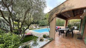 Uma área de pátio com piscina, móveis para área externa e um pergolado.