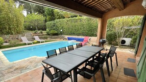 Um pátio externo com piscina, mesa de jantar e cadeiras.