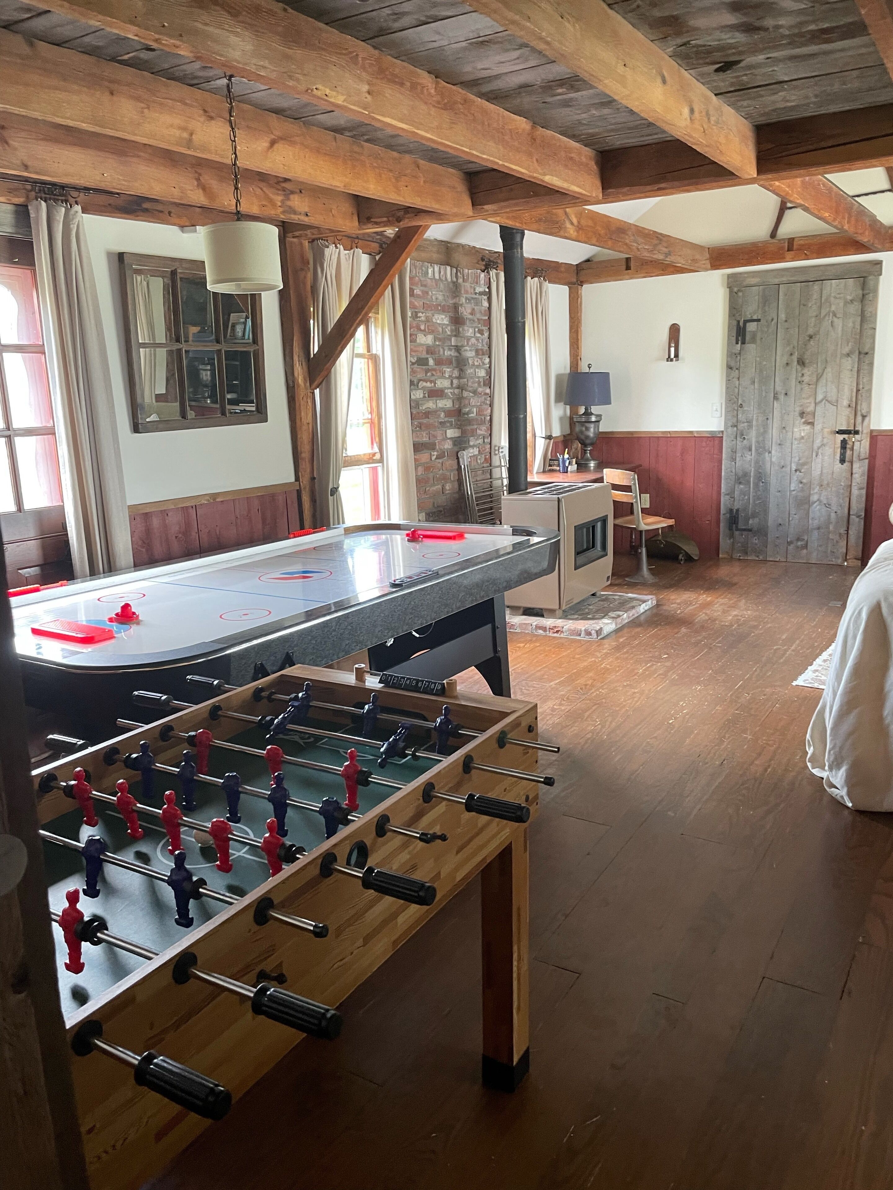 A room with a foosball table, a ping pong table, and a billiards table.