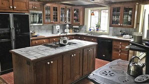 Une cuisine avec des meubles de rangement en bois, un îlot central, une cuisinière et un réfrigérateur.