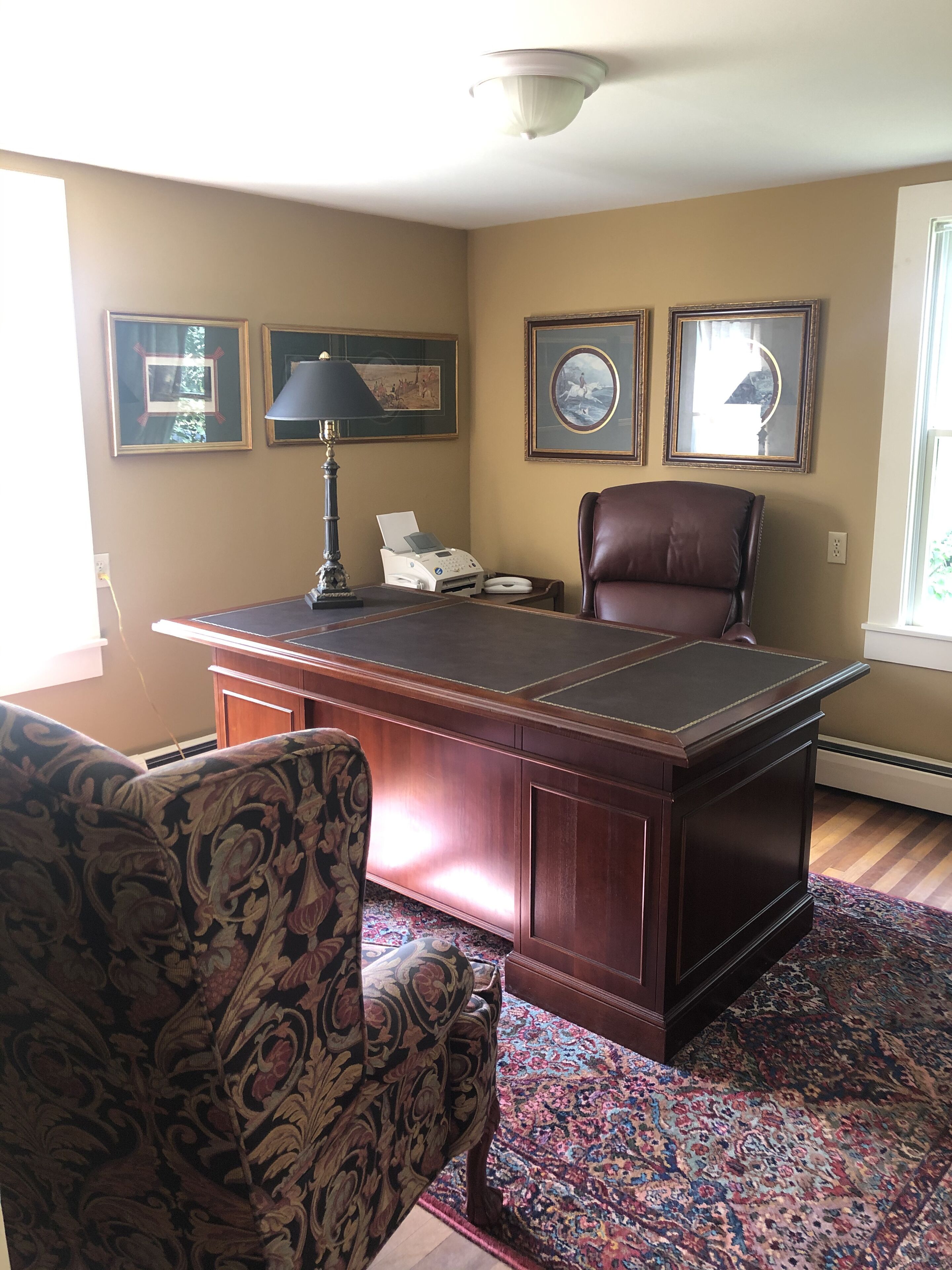 Un bureau spacieux, doté d’un grand bureau, d’un fauteuil en cuir et d’un tapis à motifs.