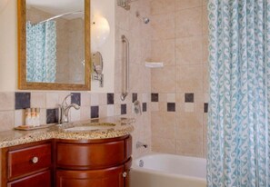 Sink, mirror, and vanity with a shower area and tub.