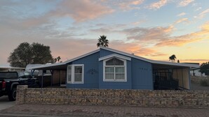 A single-story house with a stone wall in front, a garage, and a clear sky with clouds.