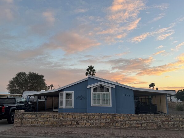 A single-story house with a stone wall in front, a garage, and a clear sky with clouds.