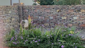 A garden with a brick wall and gravel path.
